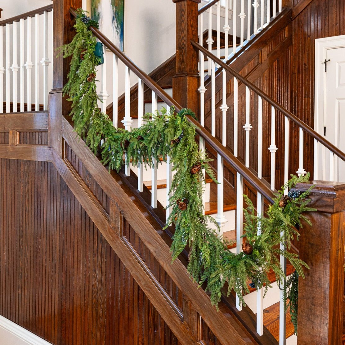 Battery operated artificial Christmas garland draped on staircase railing